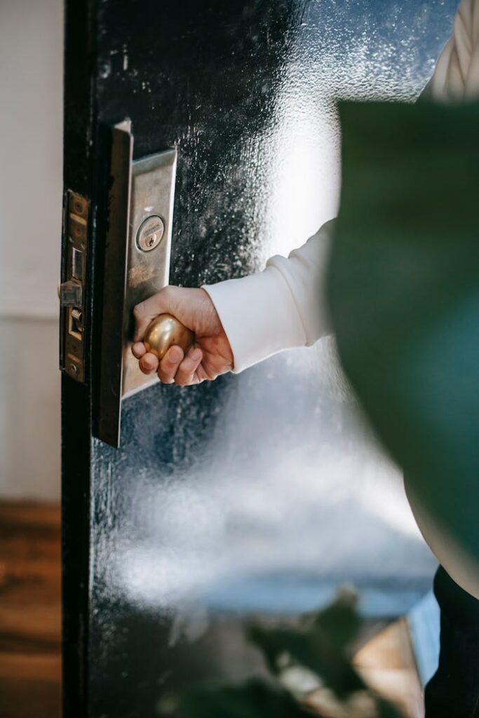 Crop person turning door handle while entering house